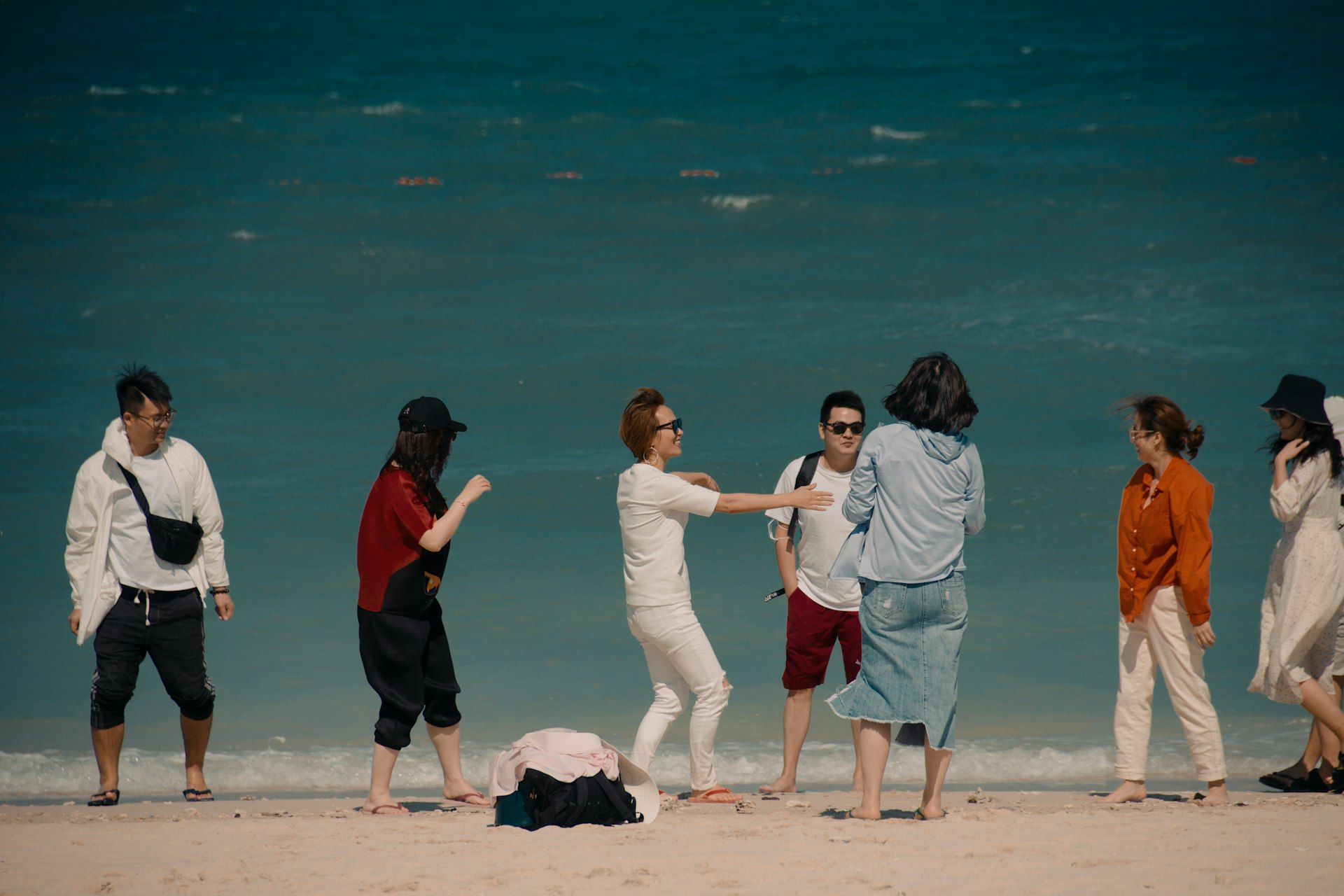 3 women and man standing on white sand beach during daytime